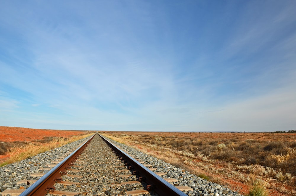 black train rail under blue sky during daytime