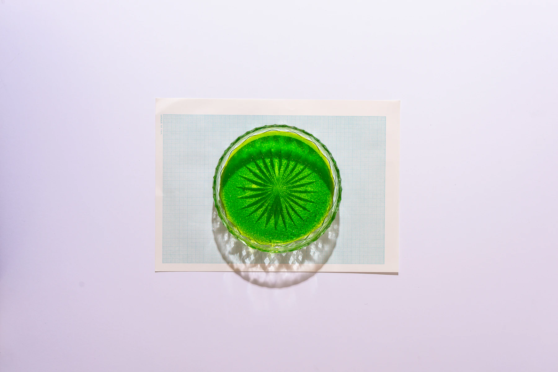 A bright green pressed-glass dish with a starburst base, photographed from directly above