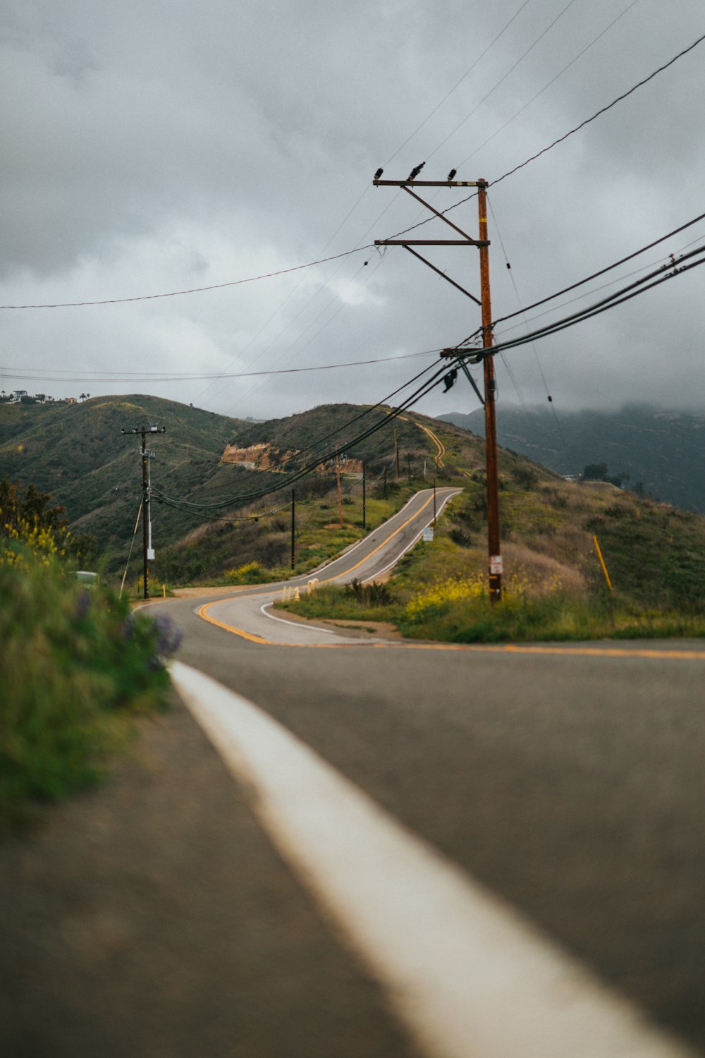 gray concrete road near green mountain under white sky during daytime