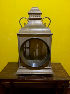 A classic marine ship lantern with intricate metalwork, resting on a polished surface.