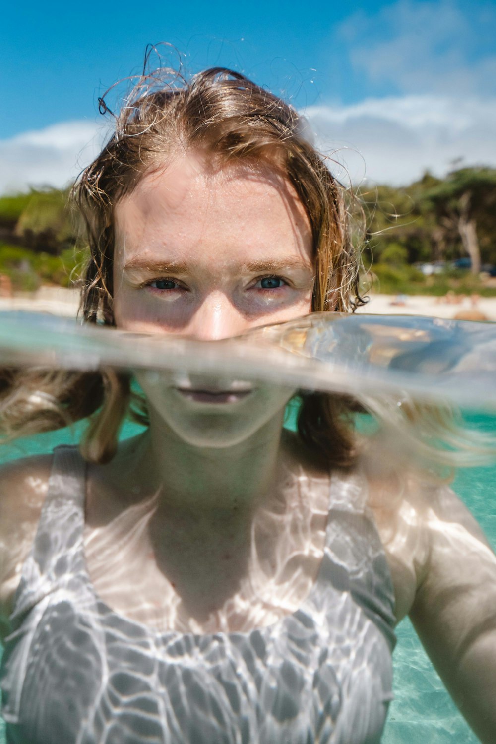 woman in white and gray floral shirt with water on her face