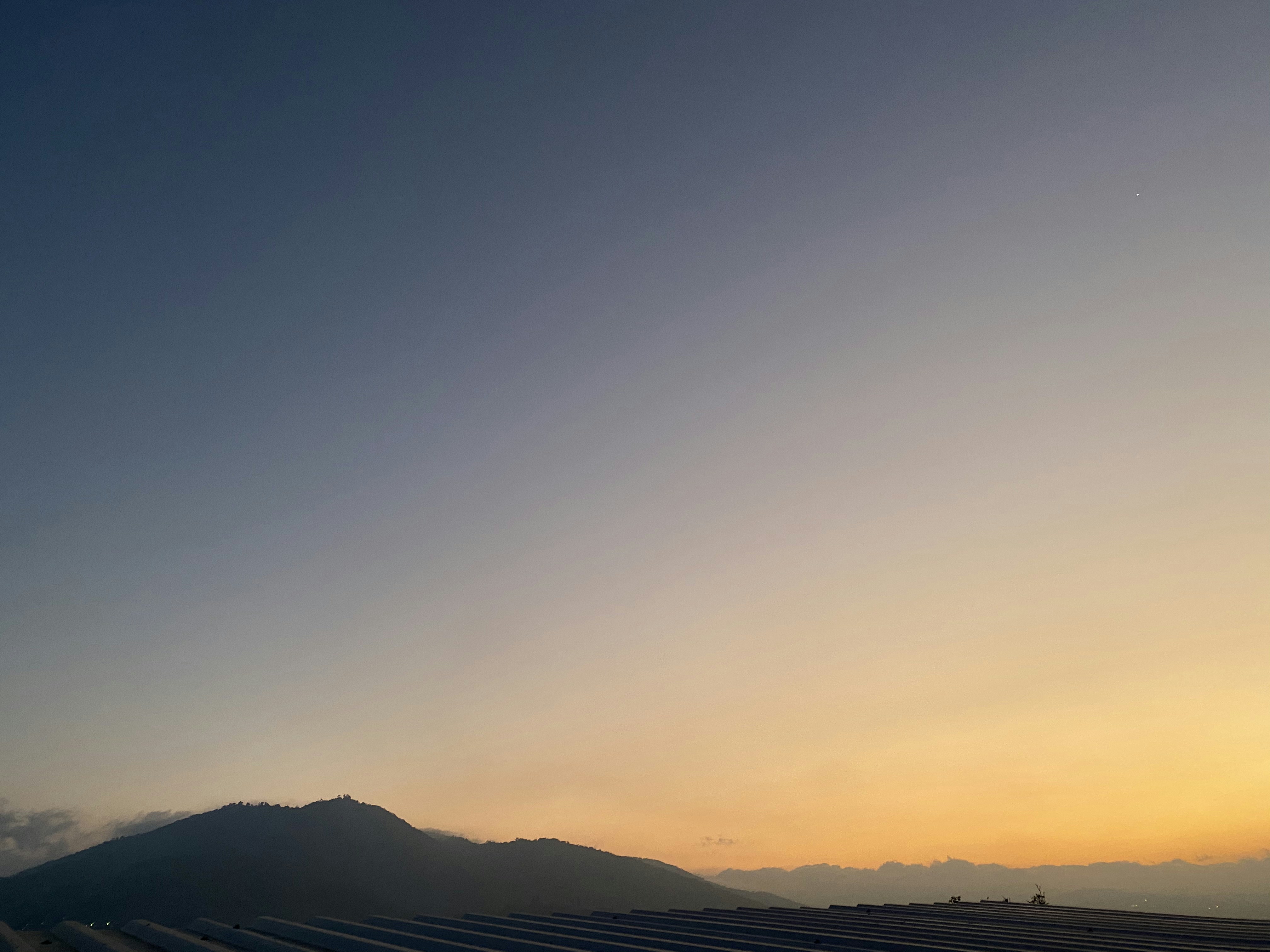 Silhouette des montagnes surplombant la ville lors d un coucher de soleil atmosphérique.
