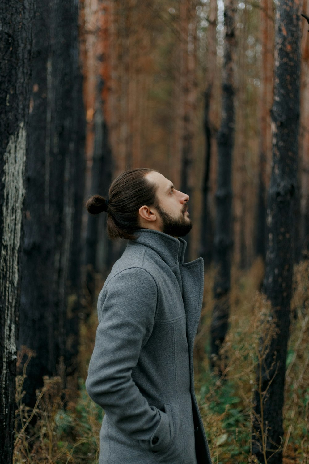 man in gray coat standing near brown tree during daytime