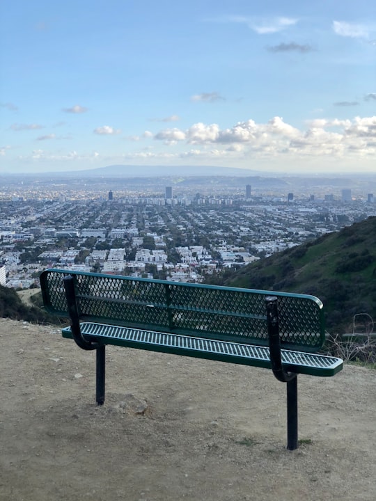 green metal bench on brown sand near body of water during daytime in Runyon Canyon Park United States