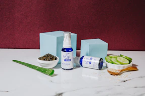 Elegant serum bottle with a dropper resting beside fresh botanical ingredients on a clean white surface