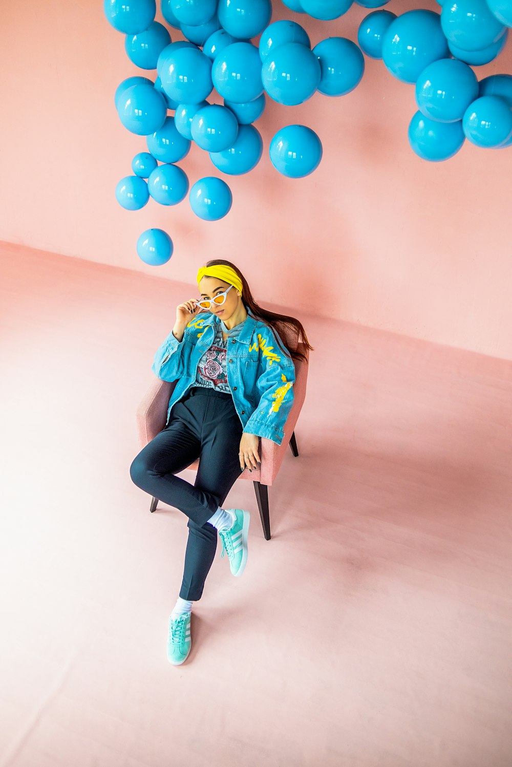 woman in blue denim jacket and black pants sitting on chair with balloons on her lap