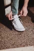 A candid shot of someone tying their sneakers, wearing a freshform white tee that fits effortlessly.