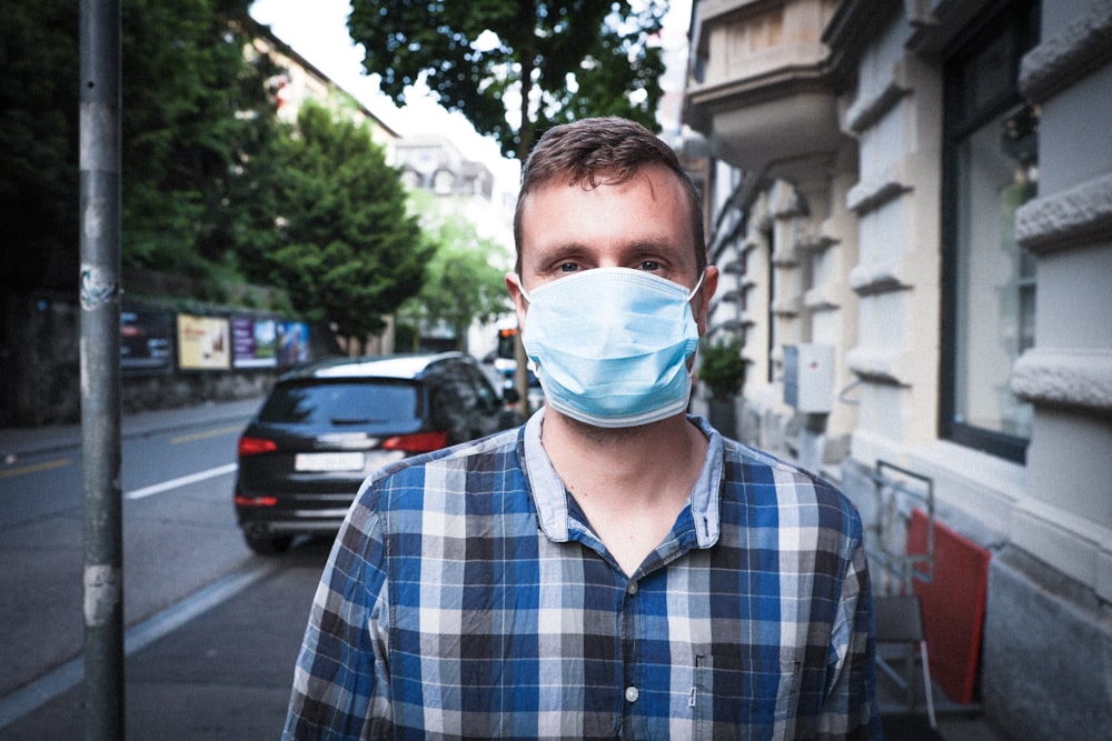 man in blue and white plaid dress shirt wearing white face mask