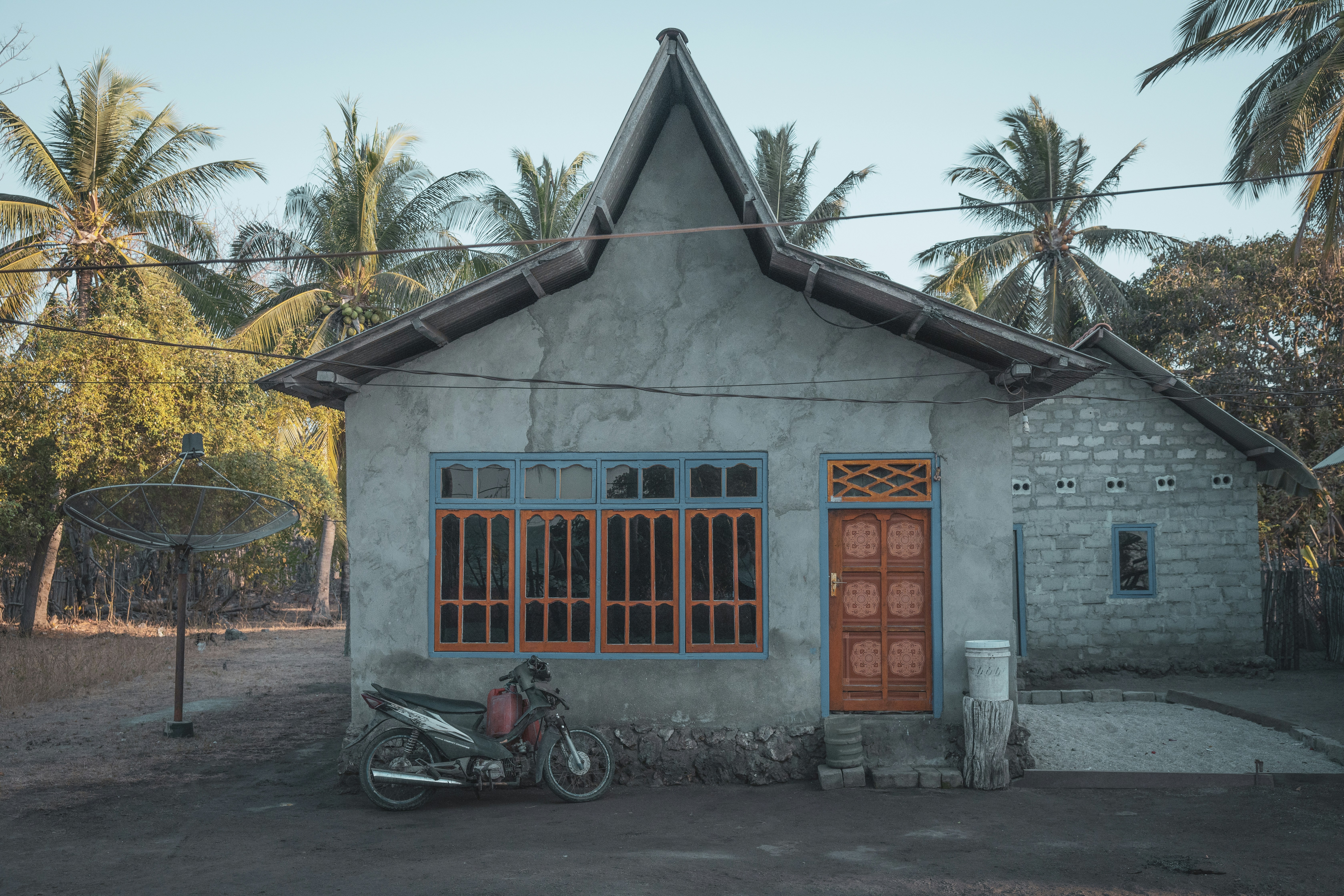 man in black shirt riding on red motorcycle near blue wooden door during daytime, A house in Indonesia