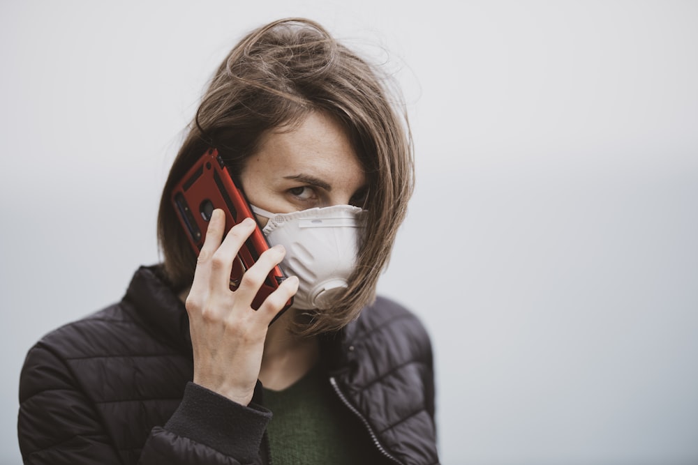 woman in black jacket covering her face with white mask