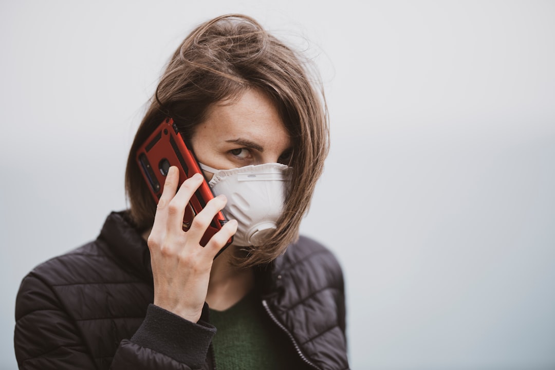 woman in black jacket covering her face with white mask