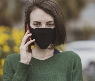 woman in green sweater holding black mask