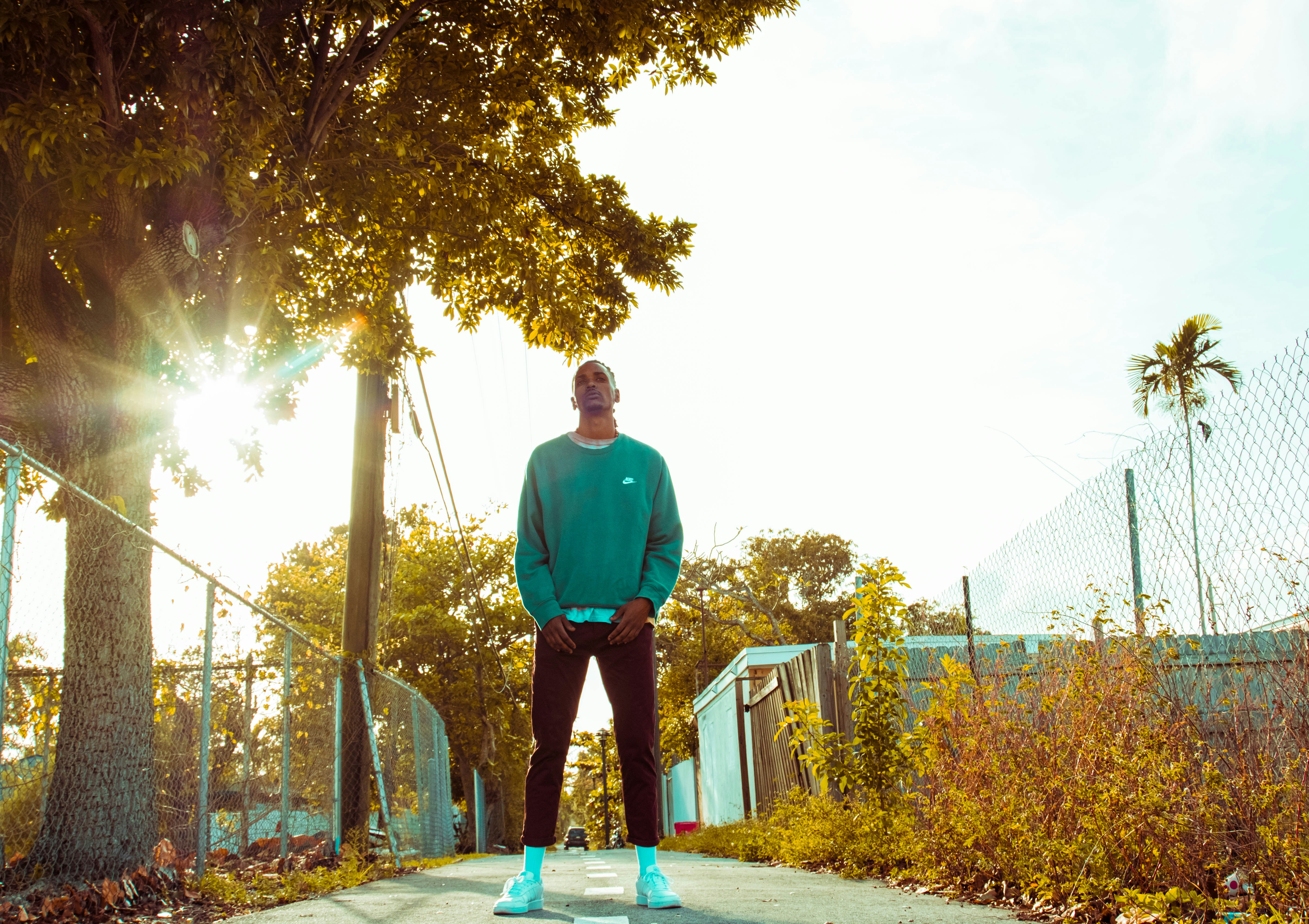 man in green sweater standing on pathway during daytime