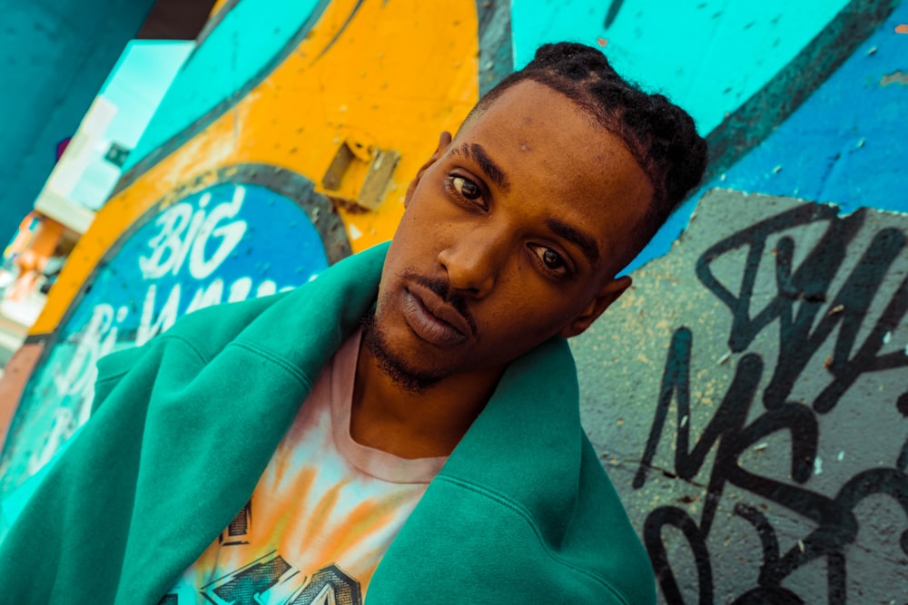 man in green hoodie standing beside wall