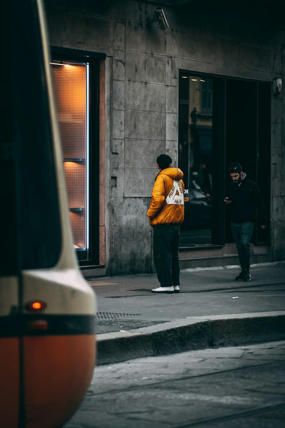 man in yellow jacket and black pants standing beside black and white train during daytime