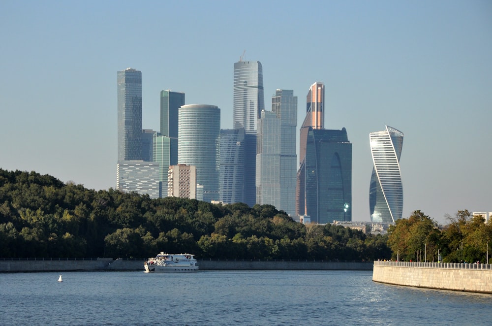 white boat on body of water near city buildings during daytime