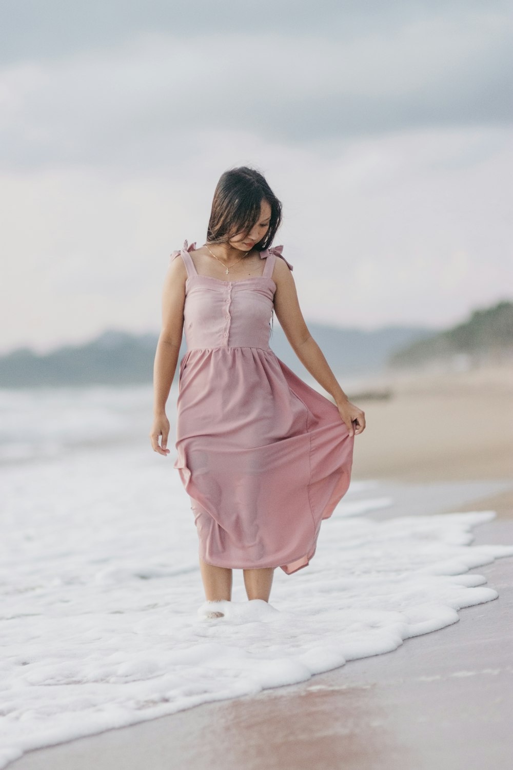 woman in pink sleeveless dress standing on beach during daytime
