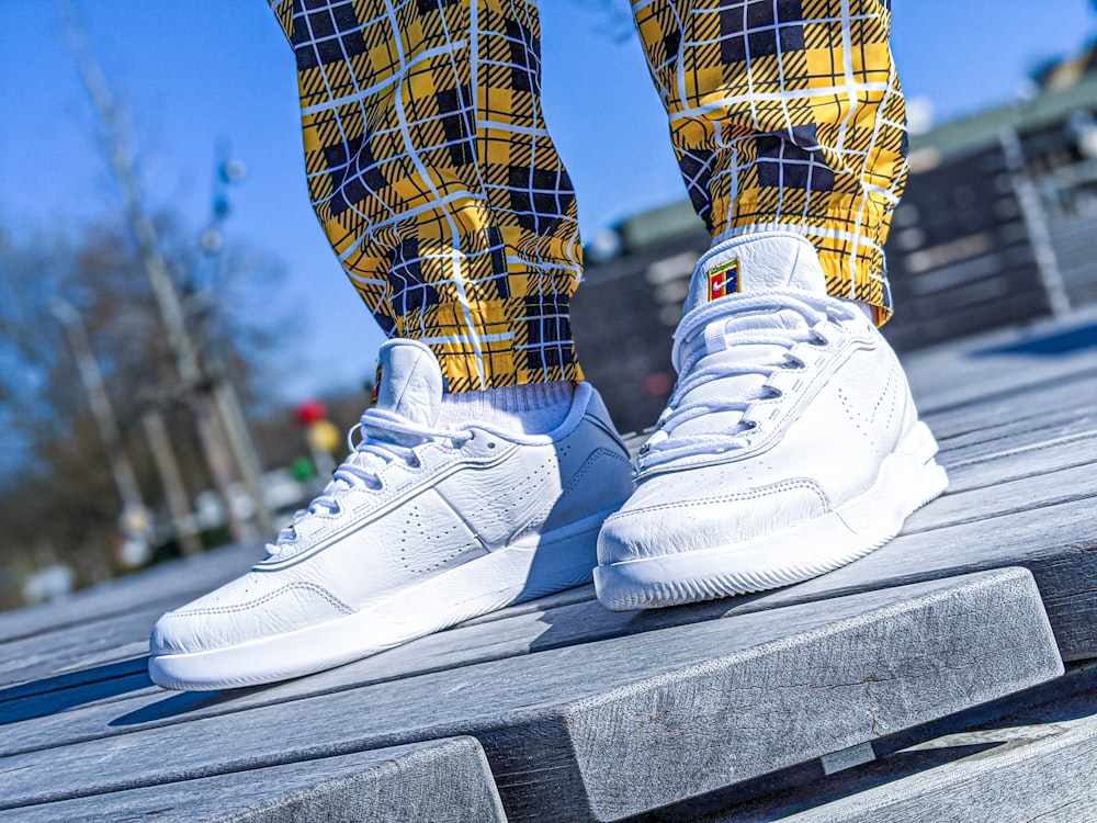 person wearing blue and yellow plaid pants and white nike sneakers