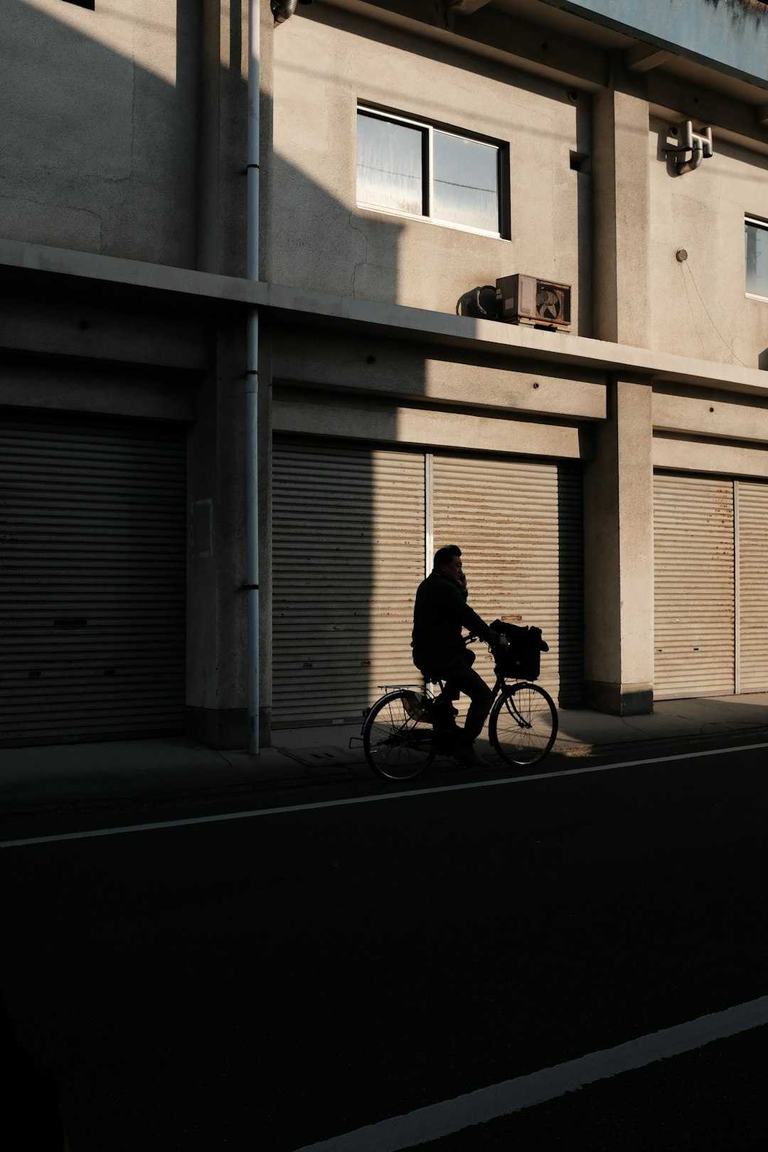 man in black jacket riding bicycle on road during daytime