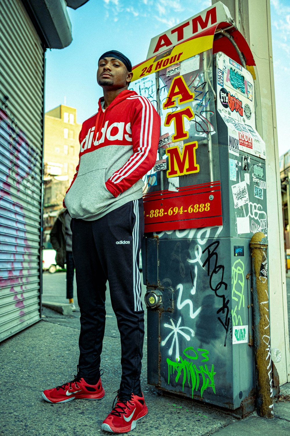 man in red and white hoodie standing beside green and white wall