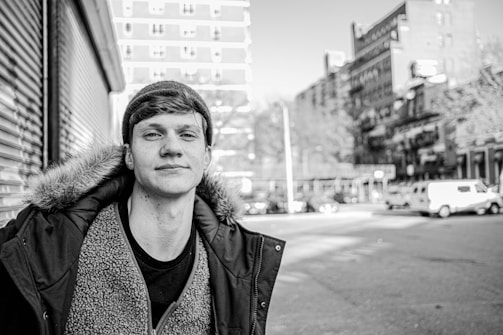 A young person wrapped in a thick winter coat, smiling softly in the snowy city streets.