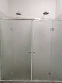 Minimalist glass shower enclosure with polished aluminum fixtures in bathroom.