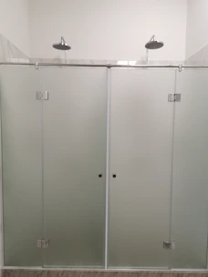 Elegant frosted glass shower enclosure with brushed metal frame in a cozy bathroom.