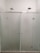 A modern shower setup with frosted glass doors and two overhead showerheads. The setting is minimalistic with clean, straight lines and a focus on functionality.