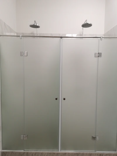 A sleek walk-in shower with glass doors, textured floor, and a handheld showerhead.