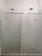 A modern shower setup with frosted glass doors and two overhead showerheads. The setting is minimalistic with clean, straight lines and a focus on functionality.