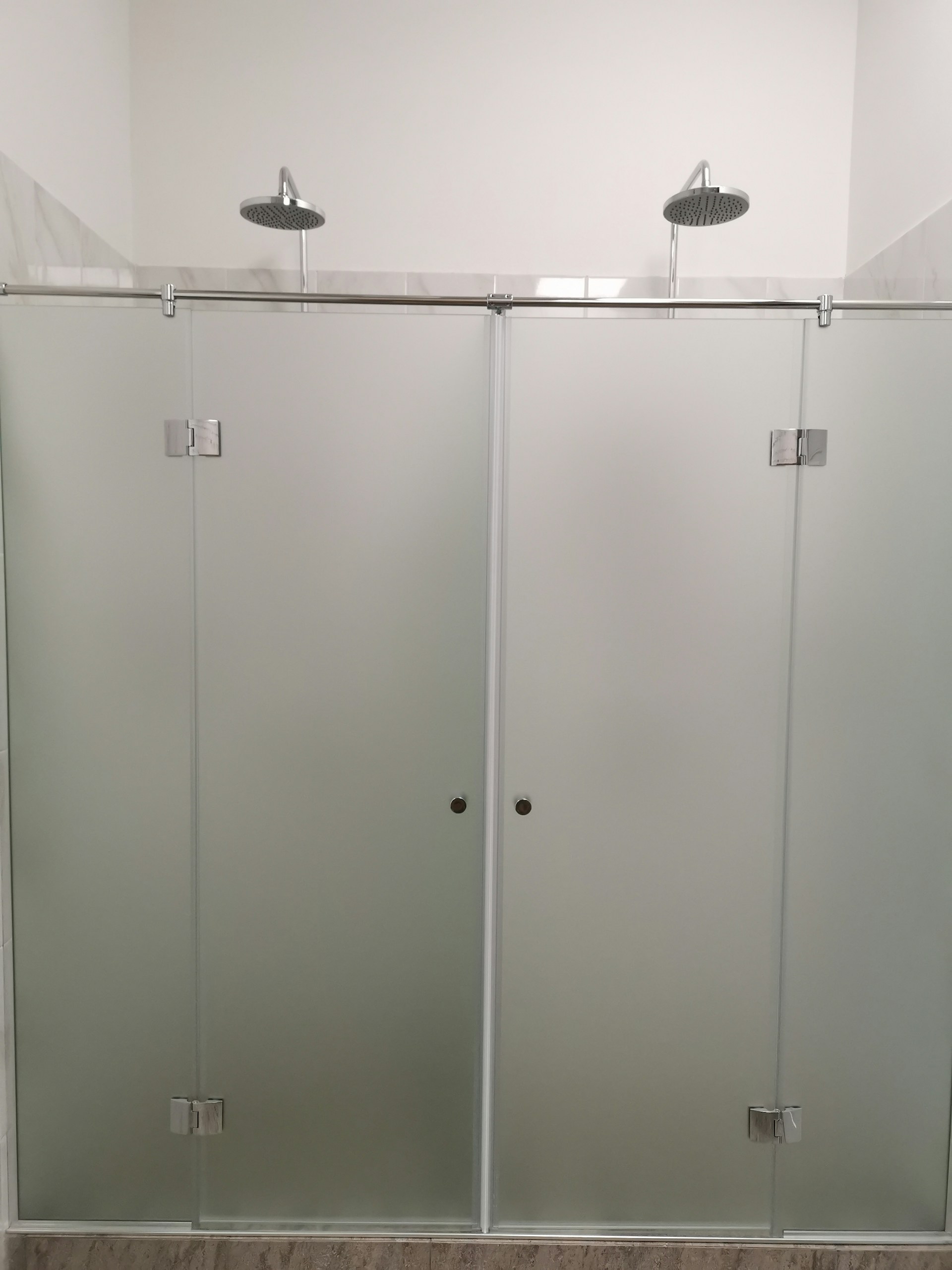 A sleek, frameless glass shower door installed in a modern bathroom, showcasing crystal-clear glass and polished hardware.