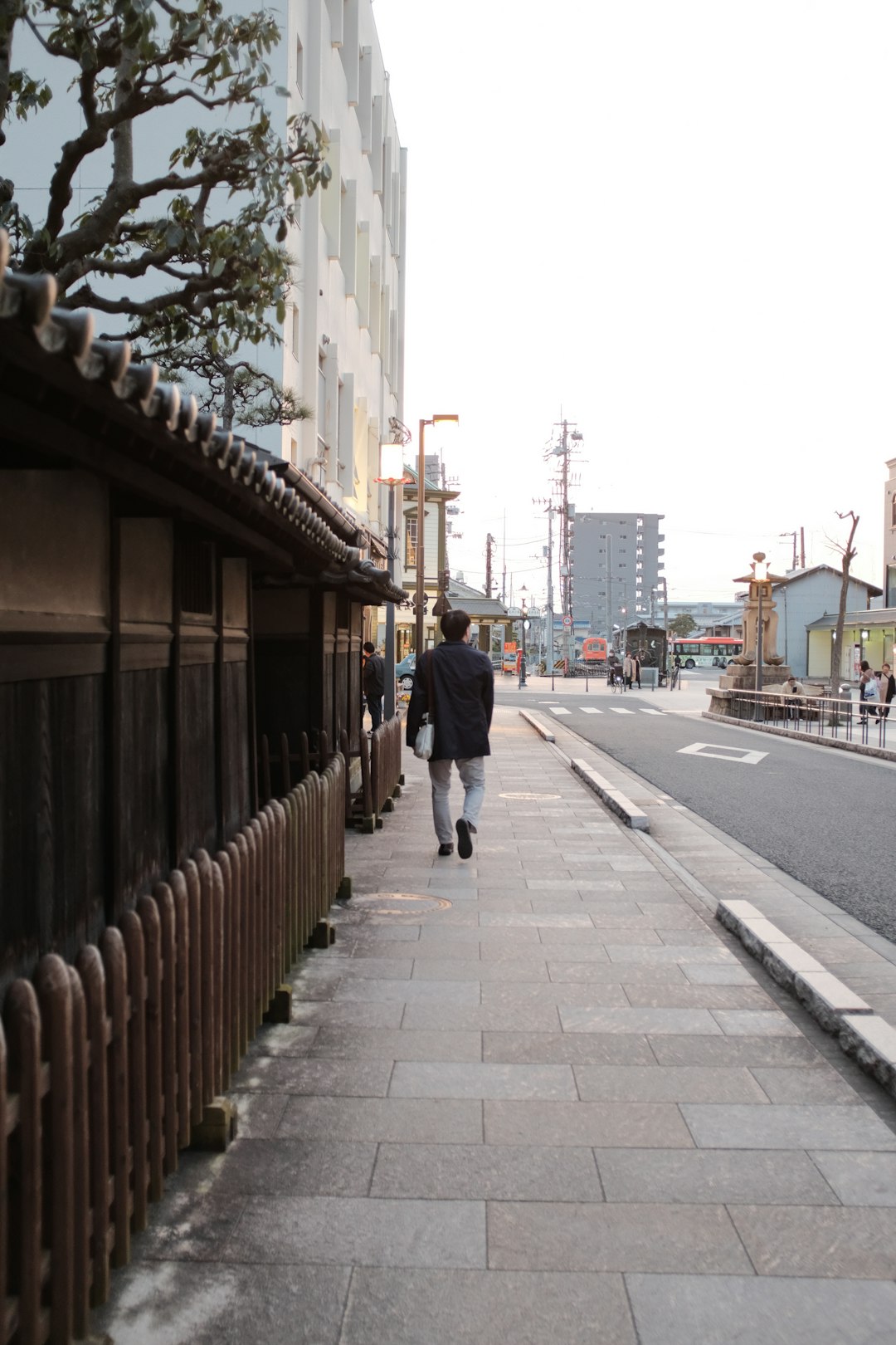 man in blue jacket walking on sidewalk during daytime