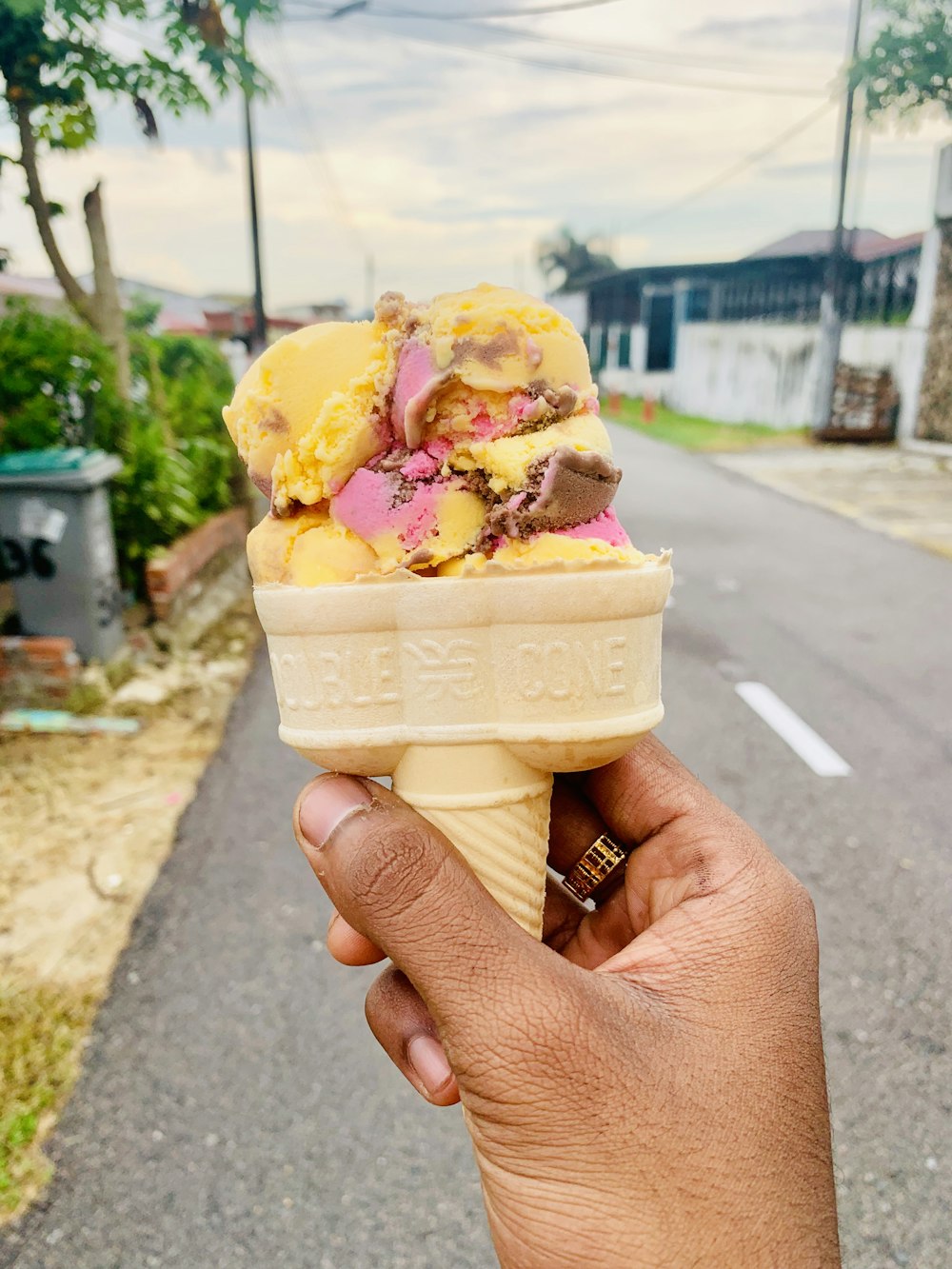 person holding ice cream cone with yellow ice cream