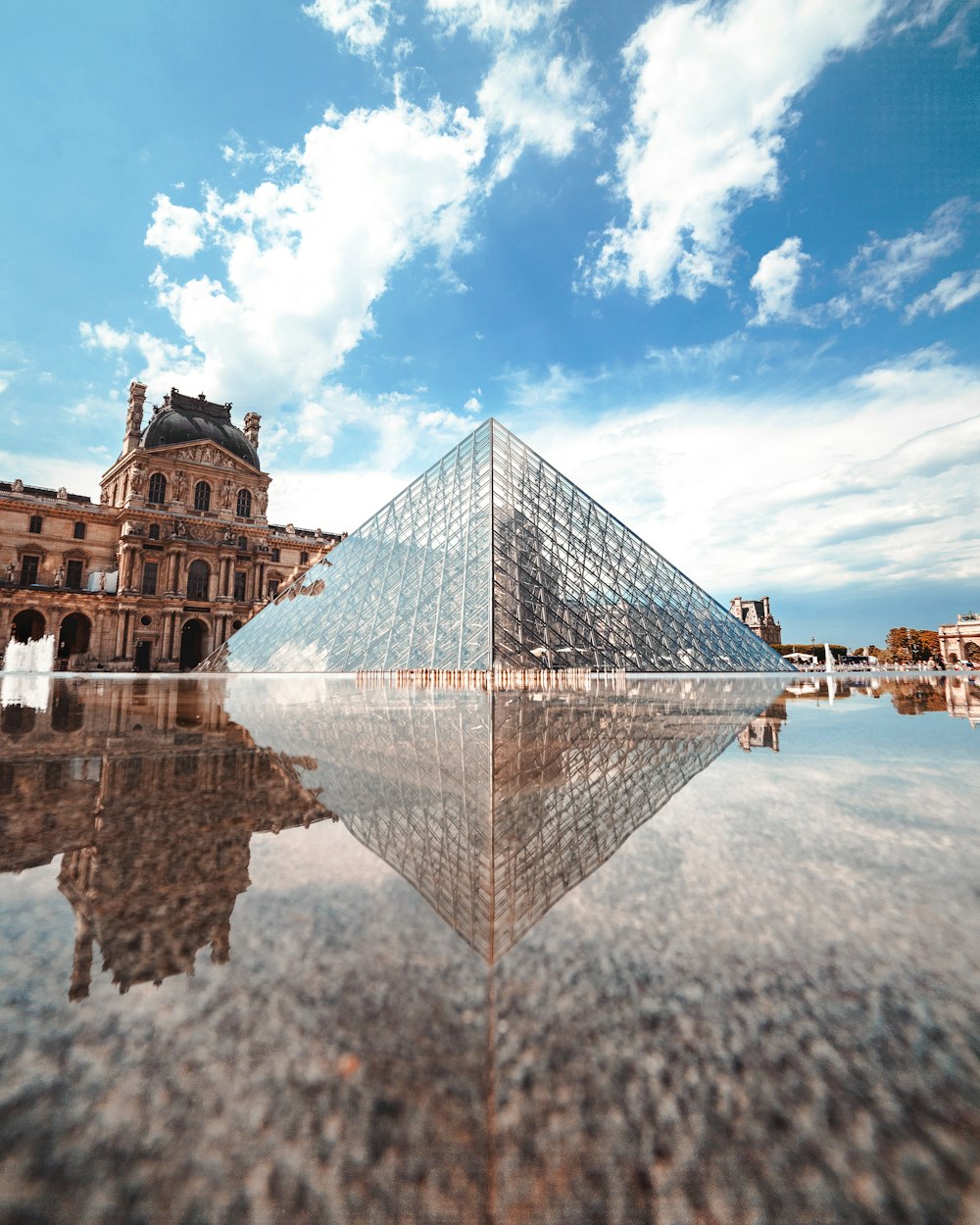 glass pyramid building near body of water during daytime