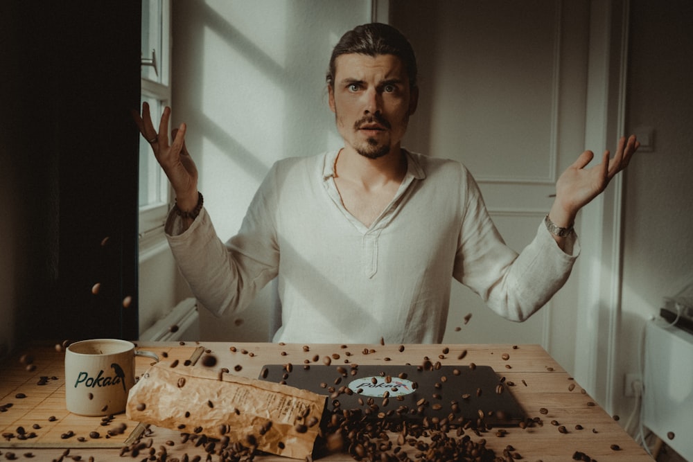 man in white v neck long sleeve shirt holding brown and black cake