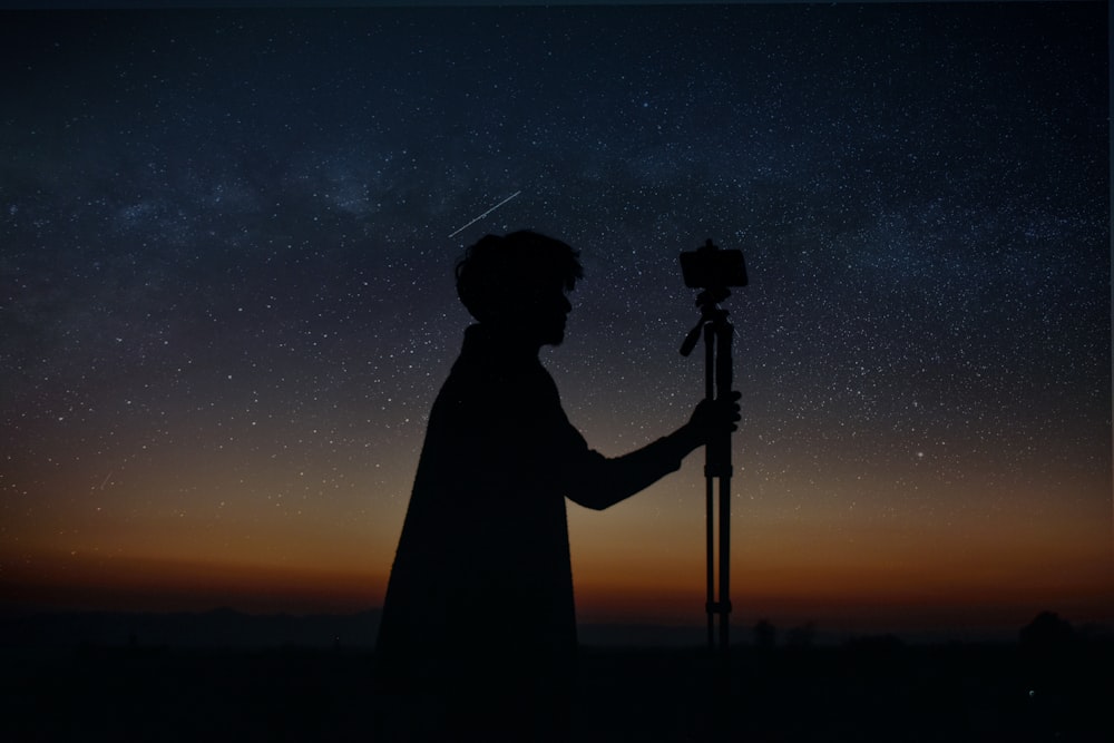silhouette of man holding camera during night time