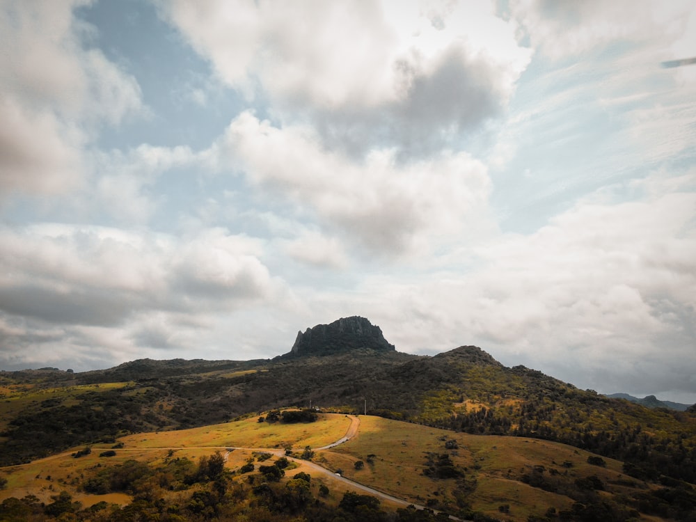 brown and green mountain under white clouds and blue sky during daytime