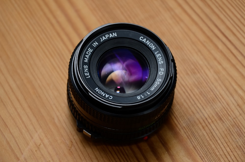 black canon camera lens on brown wooden table