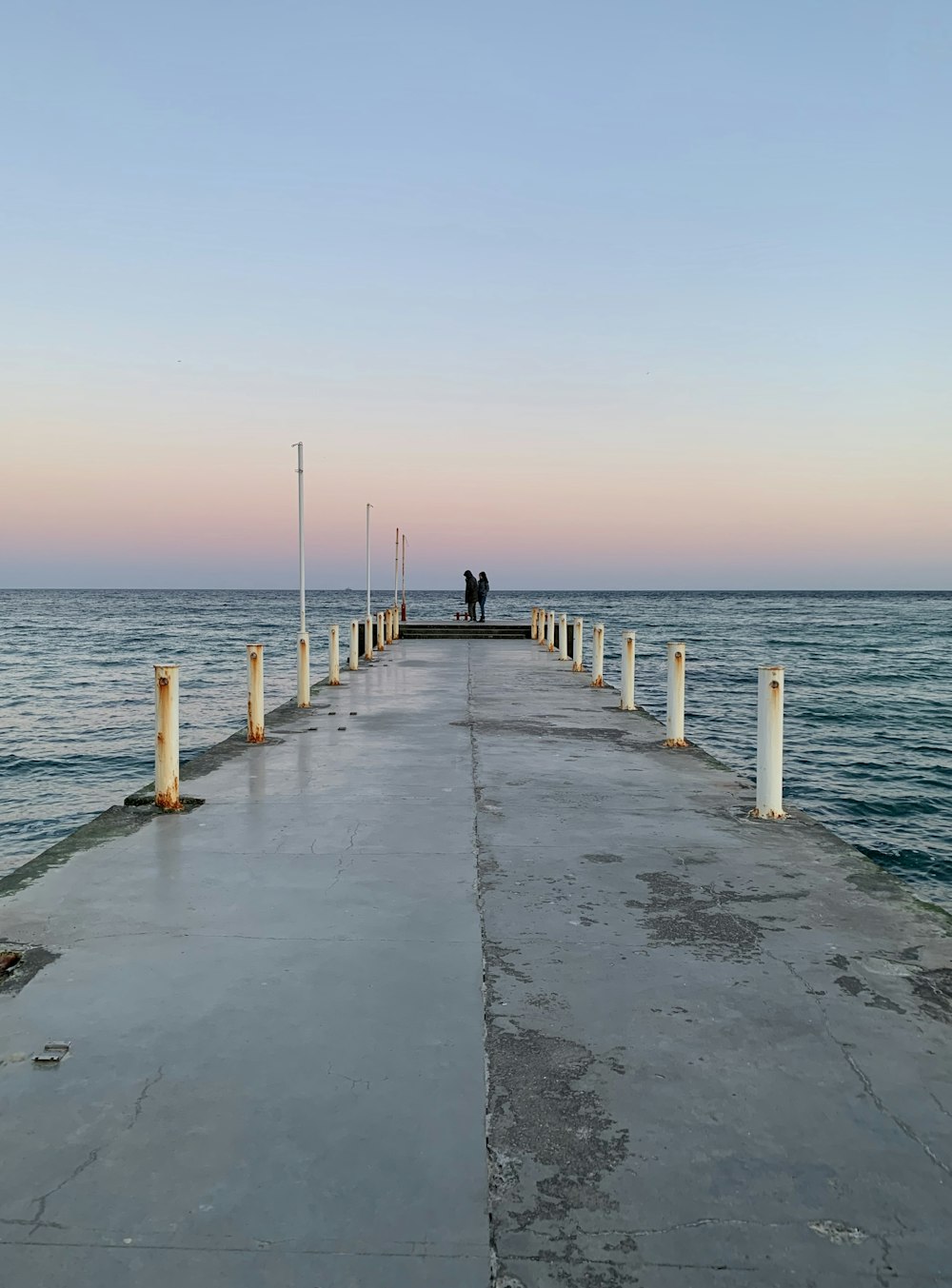 Persone che camminano sul molo di legno durante il tramonto