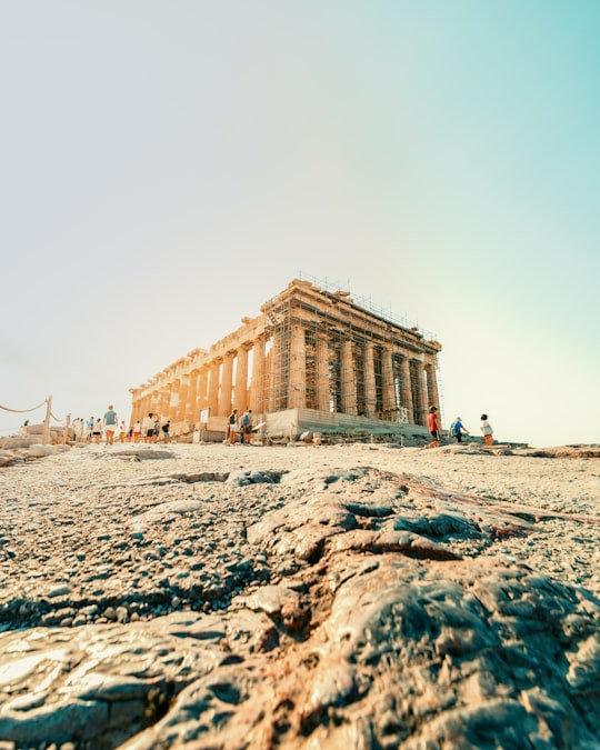 people walking on beach near brown concrete building during daytime in Acropolis of Athens Greece