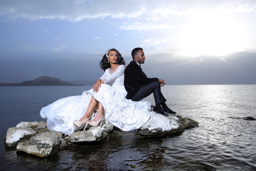 man and woman sitting on rock in the river during daytime