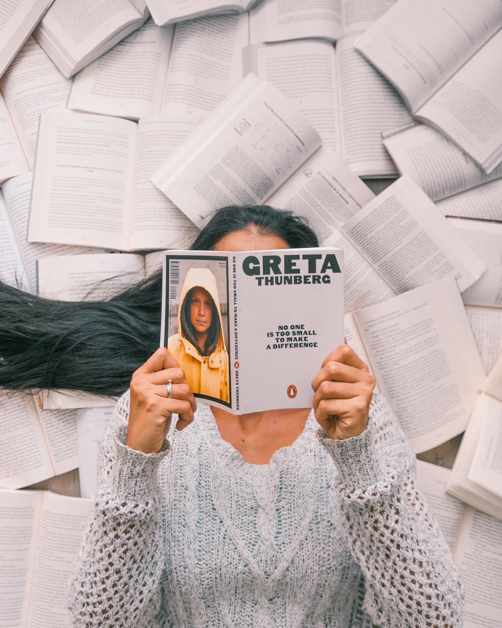 woman in white knit sweater holding white book