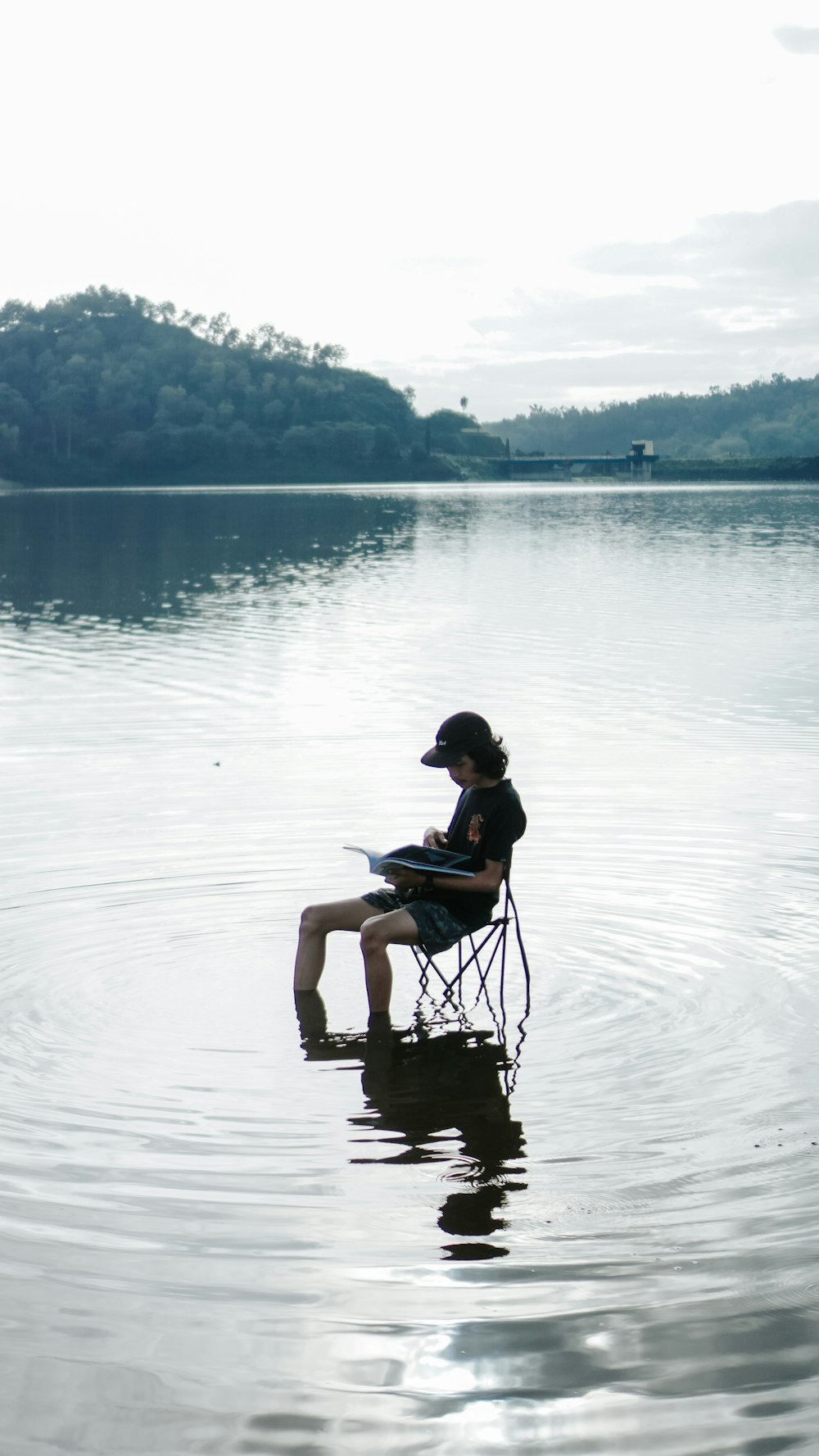 Donna in canotta nera e rosa che si siede sulla sedia nera sull'acqua durante il giorno