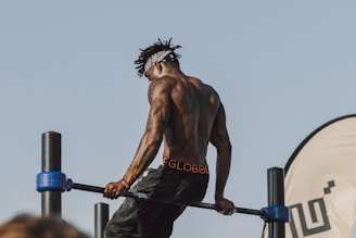 topless man in black shorts holding black exercise equipment