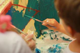 person holding paint brush painting on white and blue floral textile