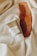 A wooden comb and a skincare product tube from The Ordinary are placed on a soft, cream-colored fabric. The items are carefully arranged, providing a cozy and natural aesthetic.