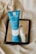 A blue tube of skincare product labeled 'Effaclar' from La Roche-Posay is placed on a mirror, reflecting next to a smaller white and blue tube. The background consists of a beige fabric, giving the setting a soft and natural texture.