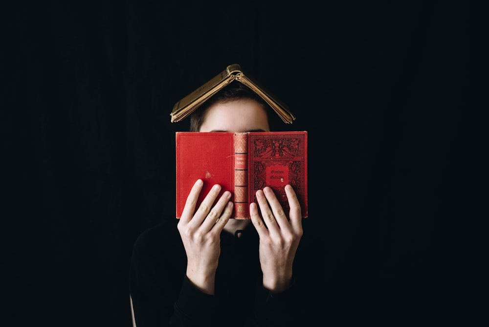 person holding red hardbound book