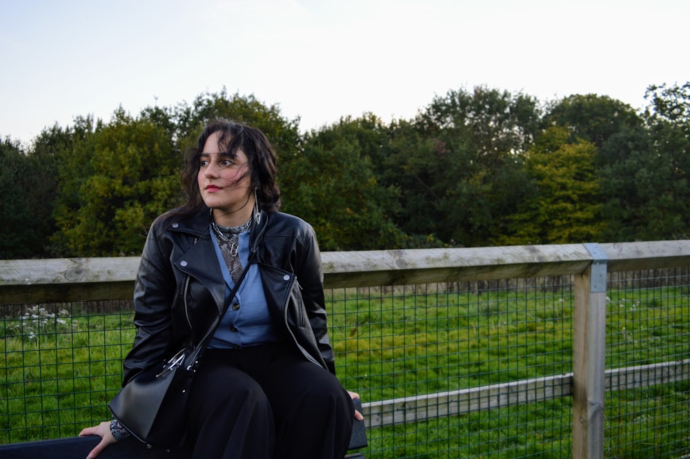 woman in black leather jacket sitting on black chair