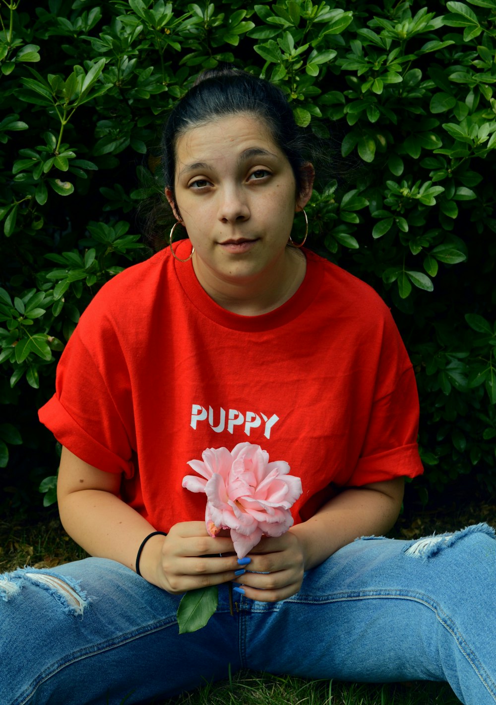 woman in red crew neck t-shirt and blue denim jeans sitting on gray textile